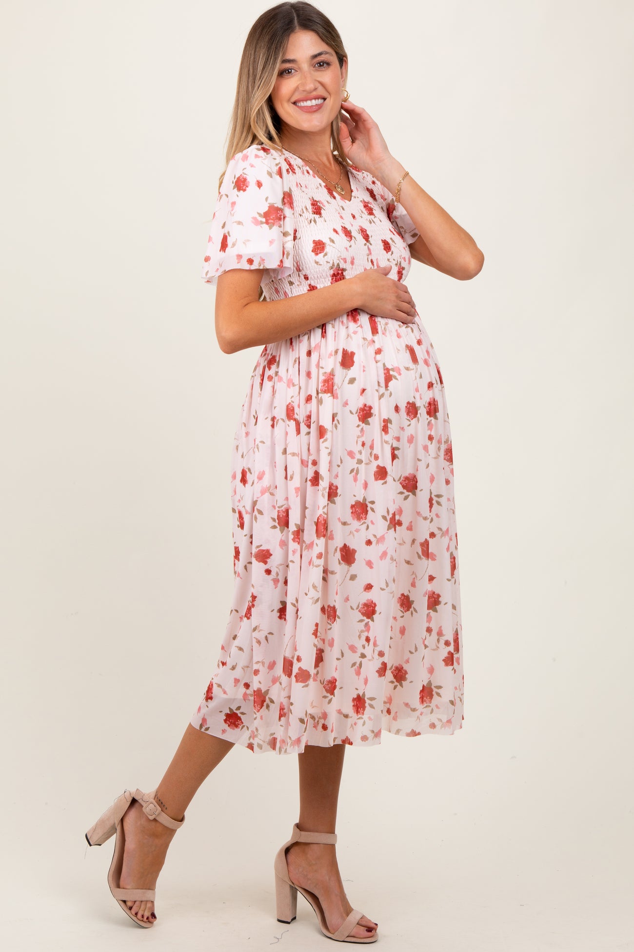 woman wearing a floral maternity dress with puff sleeves and a fitted bodice, showing her baby bump