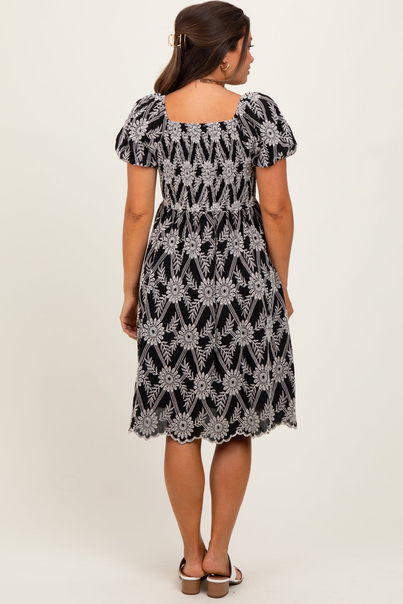 woman wearing a black and white floral print maternity dress with puff sleeves and a smocked waist