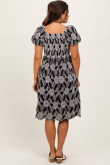 woman wearing a black and white floral print maternity dress with puff sleeves and a smocked waist