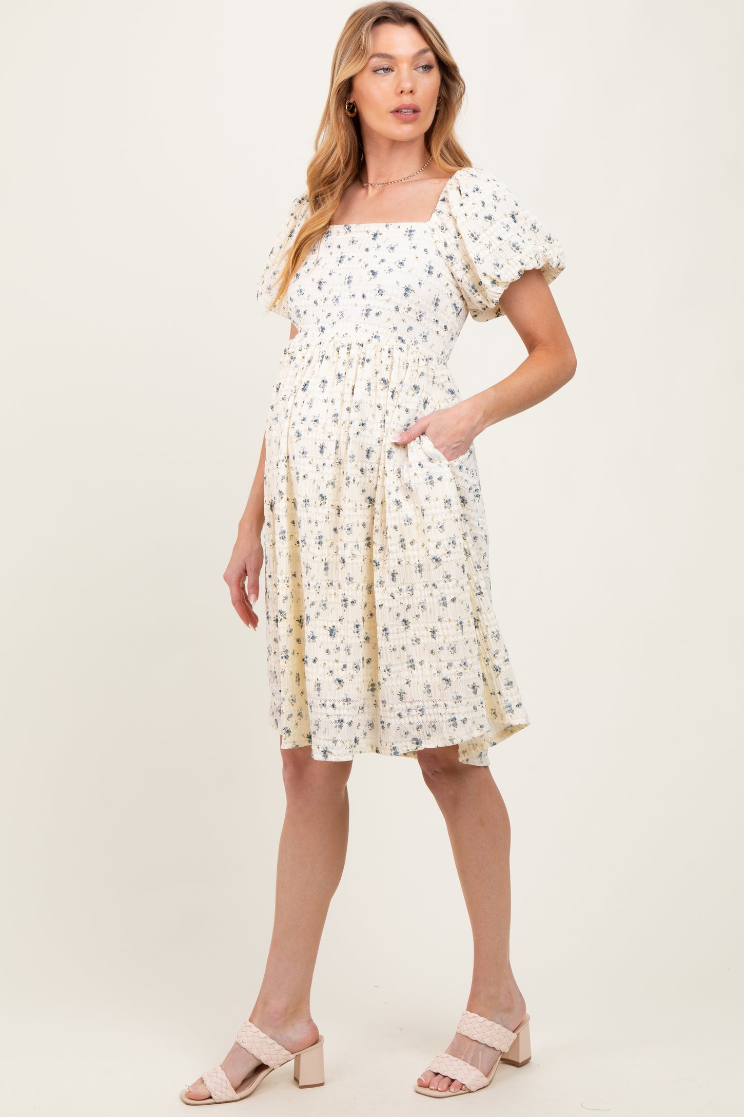 woman wearing a floral print maternity dress with square neckline and puff sleeves, showing her baby bump