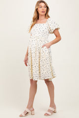 woman wearing a floral print maternity dress with square neckline and puff sleeves, showing her baby bump
