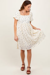 woman wearing a floral cream puff sleeve dress with a square neckline and relaxed fit, standing with one hand on the skirt