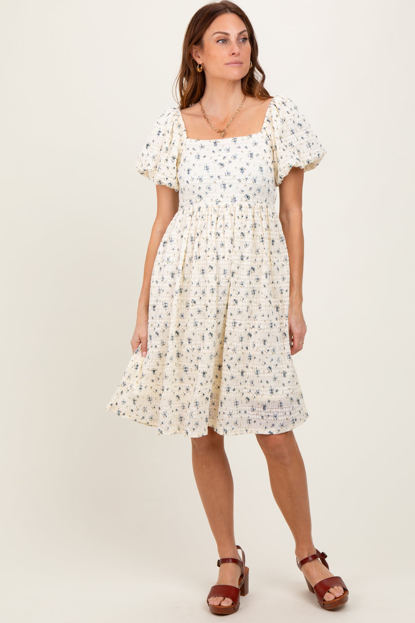 woman wearing a cream floral print puff sleeve dress with a square neckline and a flared skirt