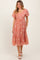woman wearing a dusty rose tiered midi dress with floral embroidery and puff sleeves