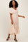 woman wearing a blush pink maxi dress with floral embroidery and flutter sleeves, standing and smiling