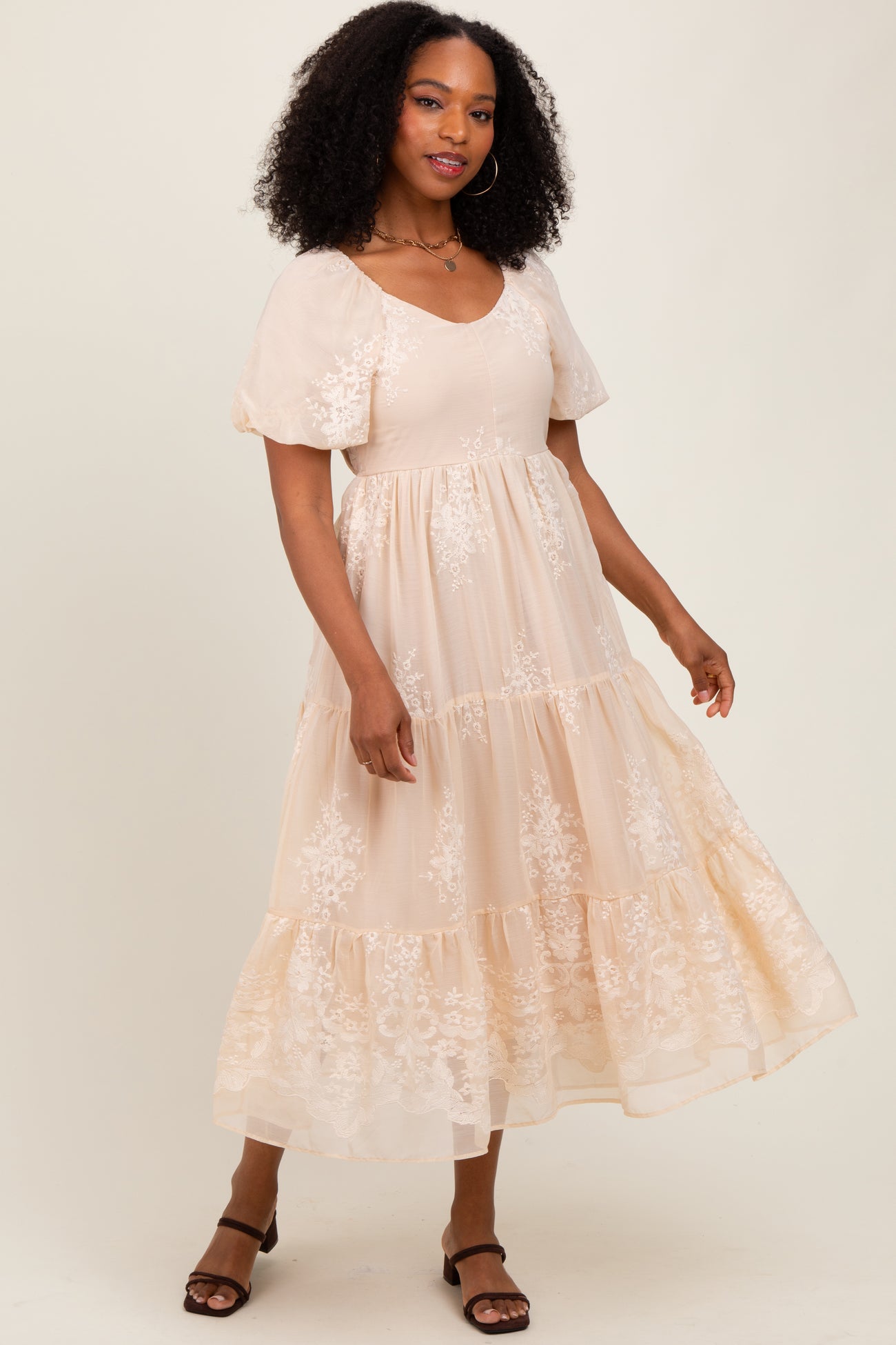 woman wearing a blush pink maxi dress with embroidered floral details and puff sleeves