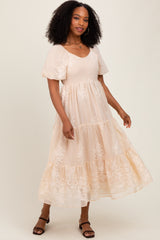 woman wearing a blush pink maxi dress with embroidered floral details and puff sleeves