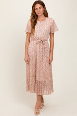 woman wearing a light pink floral midi dress with short sleeves and a tie belt at the waist