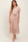 woman wearing a light pink floral midi dress with short sleeves and a tie belt at the waist