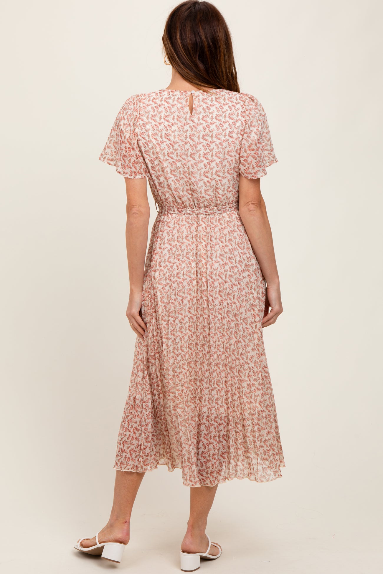 woman wearing a pink floral midi dress with short sleeves and a gathered waist, shown from the back