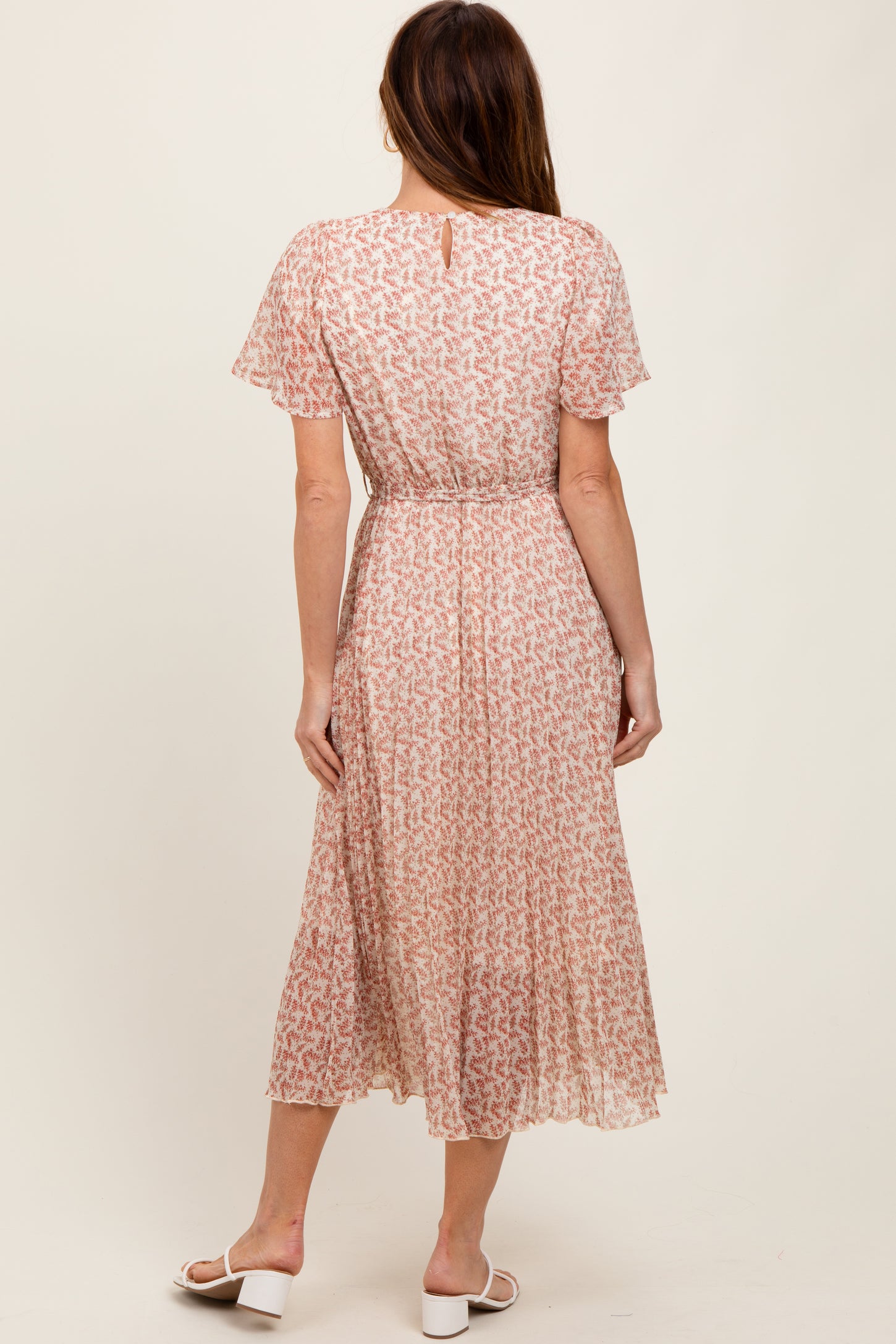 woman wearing a pink floral midi dress with short sleeves and a gathered waist, shown from the back