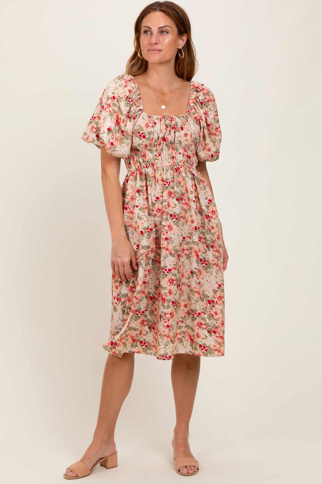 woman wearing a floral midi dress with puff sleeves and a cinched waist, standing on a neutral background