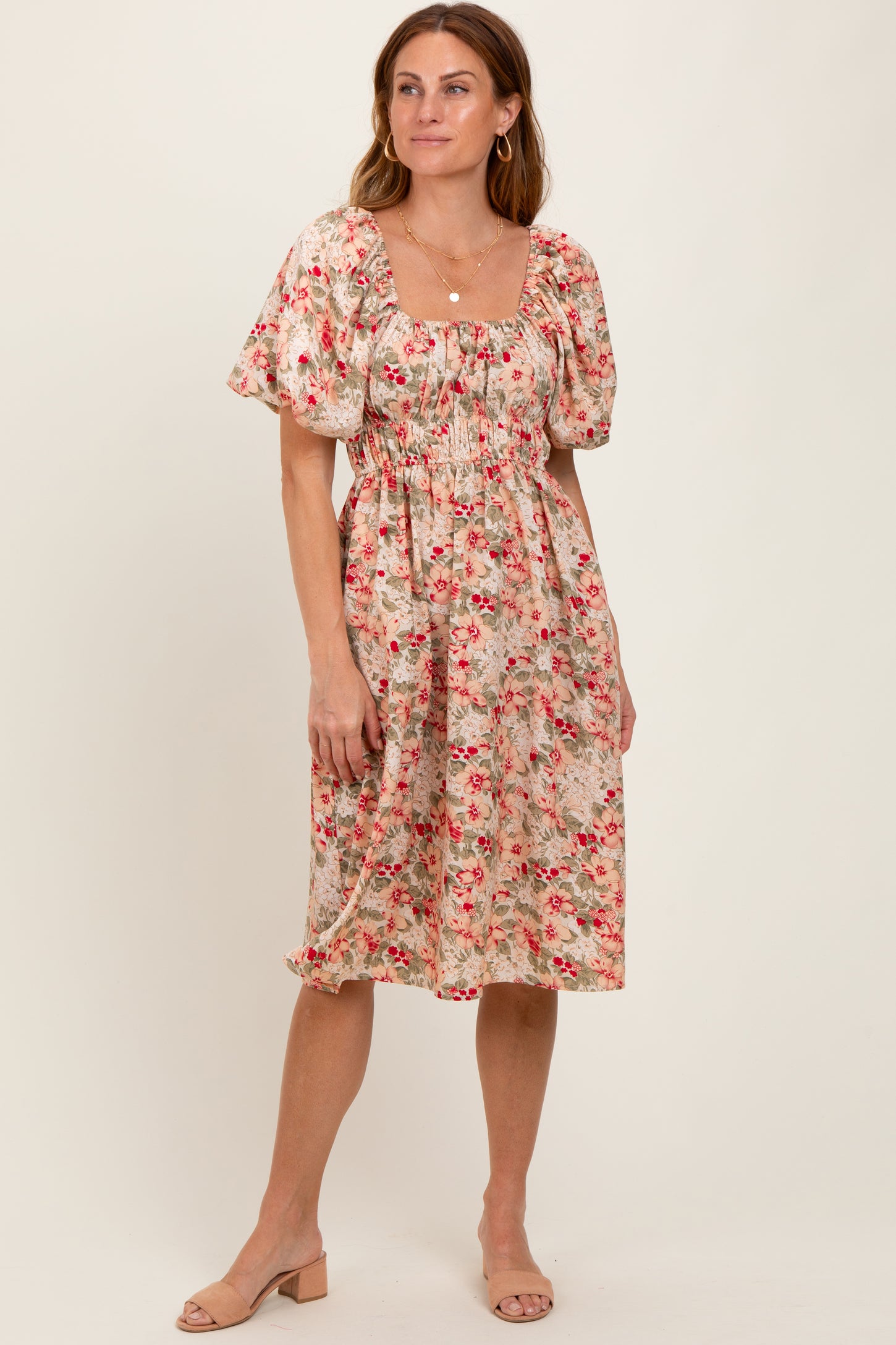 woman wearing a floral midi dress with puff sleeves and a cinched waist, standing on a neutral background