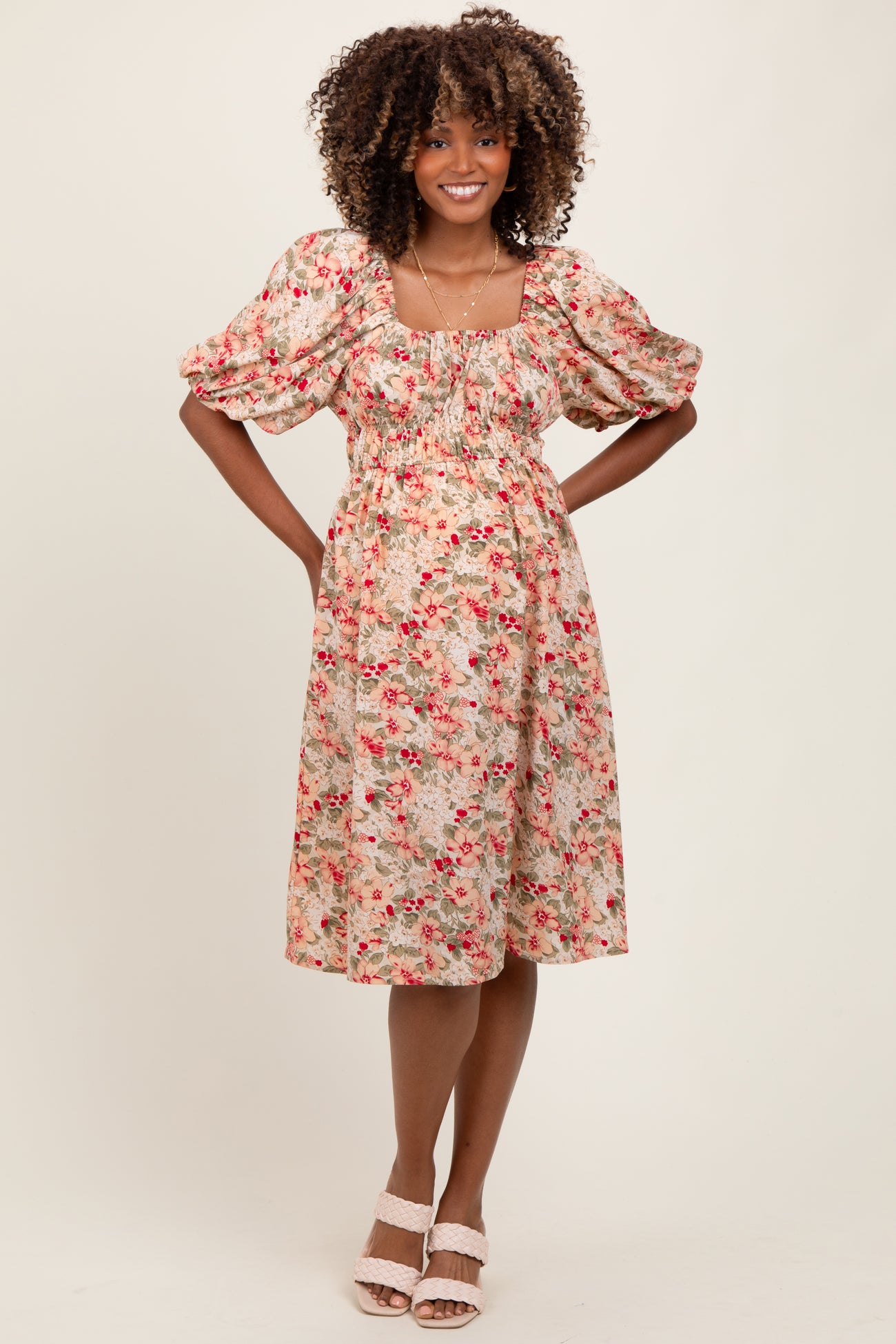 woman wearing a floral puff sleeve maternity dress with a fitted bodice and flowy skirt, baby bump visible