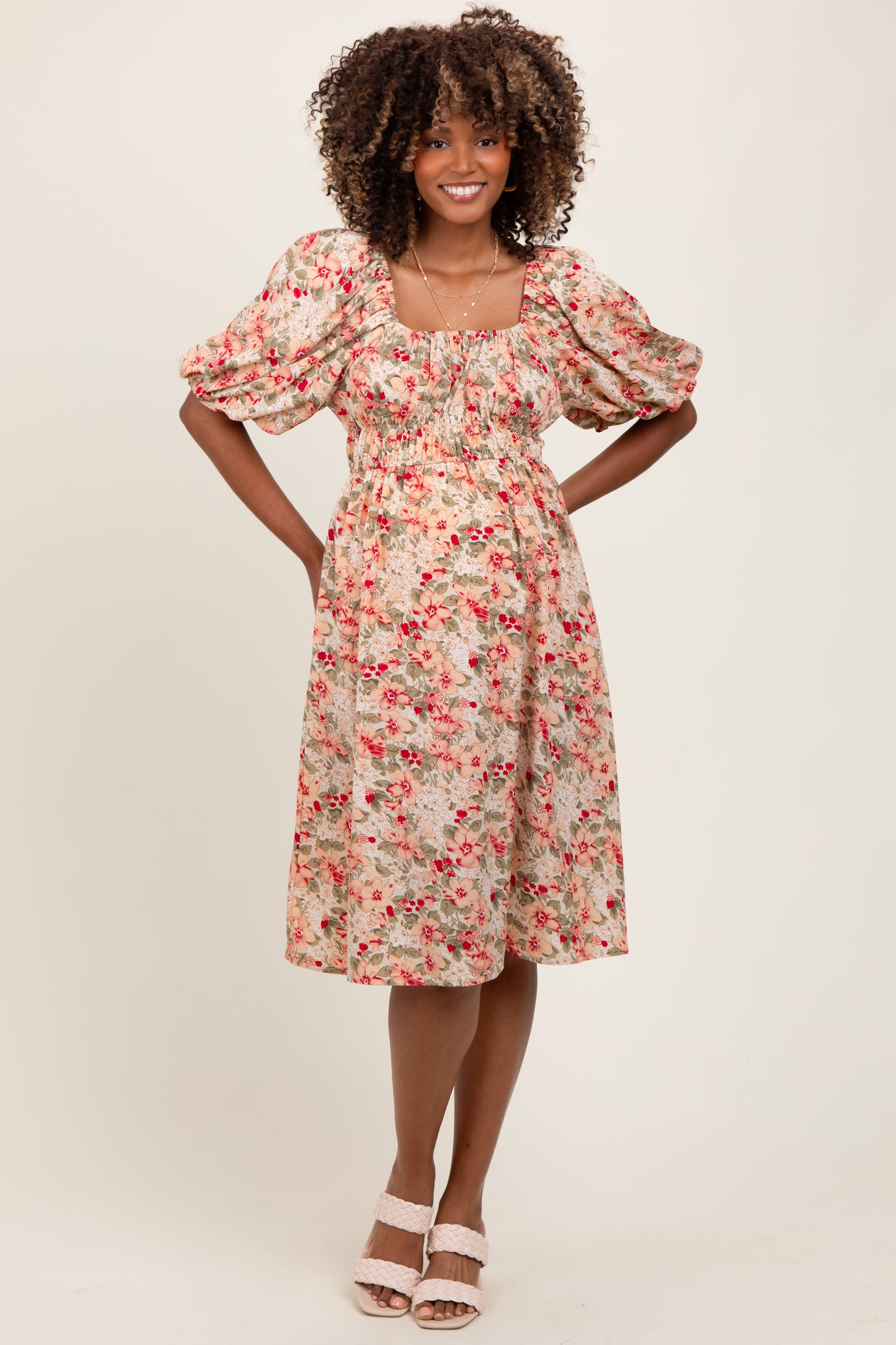 woman wearing a floral puff sleeve maternity dress with a fitted bodice and flowy skirt, baby bump visible
