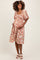 woman wearing a floral maternity dress with puff sleeves and a smocked bodice, cradling her baby bump