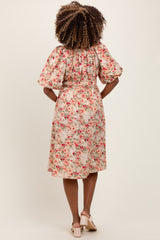 woman wearing a floral print maternity dress with puff sleeves and a cinched waist, showing off her baby bump from the back