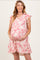 woman wearing a pink patterned maternity dress with ruffle sleeves and holding her baby bump