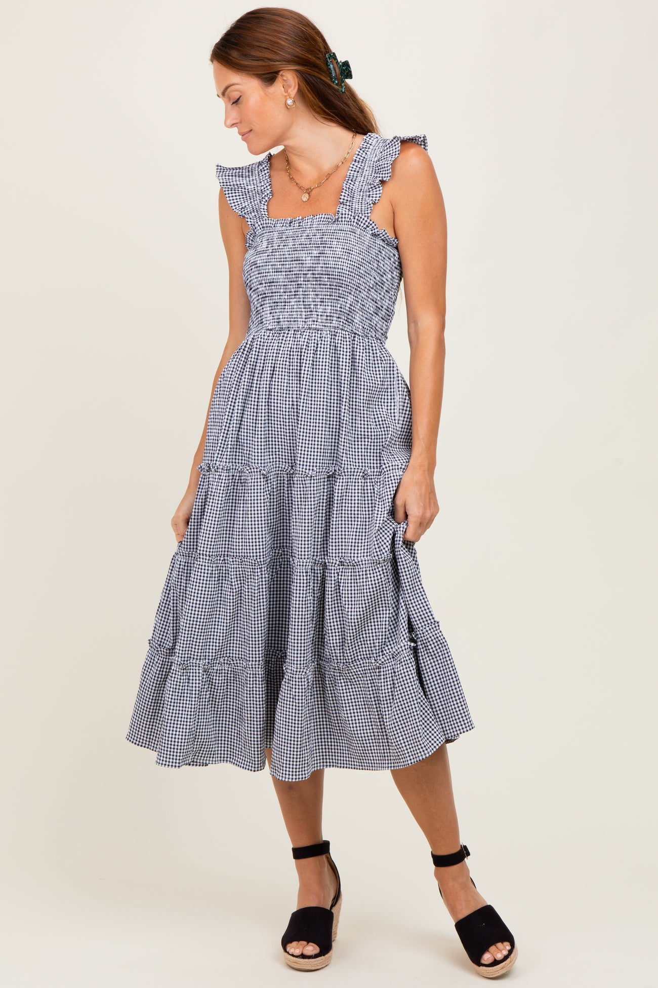 woman wearing a navy and white gingham midi dress with ruffled straps and a tiered skirt