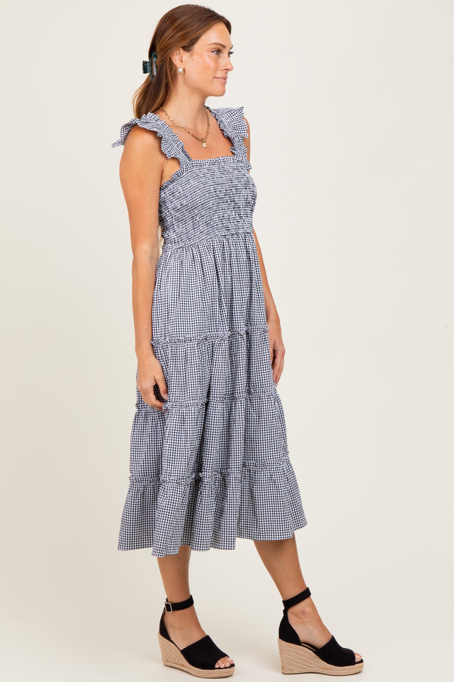 woman wearing a navy and white gingham tiered midi dress with ruffle straps and wedge sandals