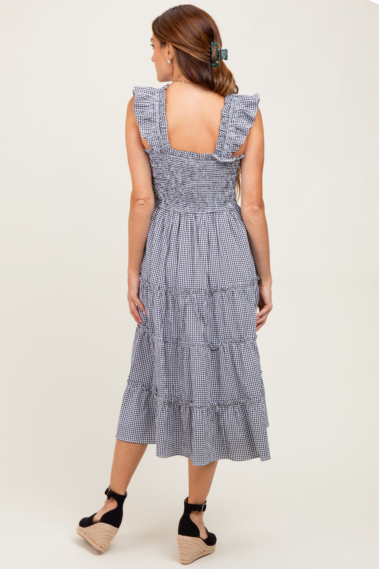 woman wearing a navy blue gingham tiered midi dress with ruffled sleeves and a smocked back