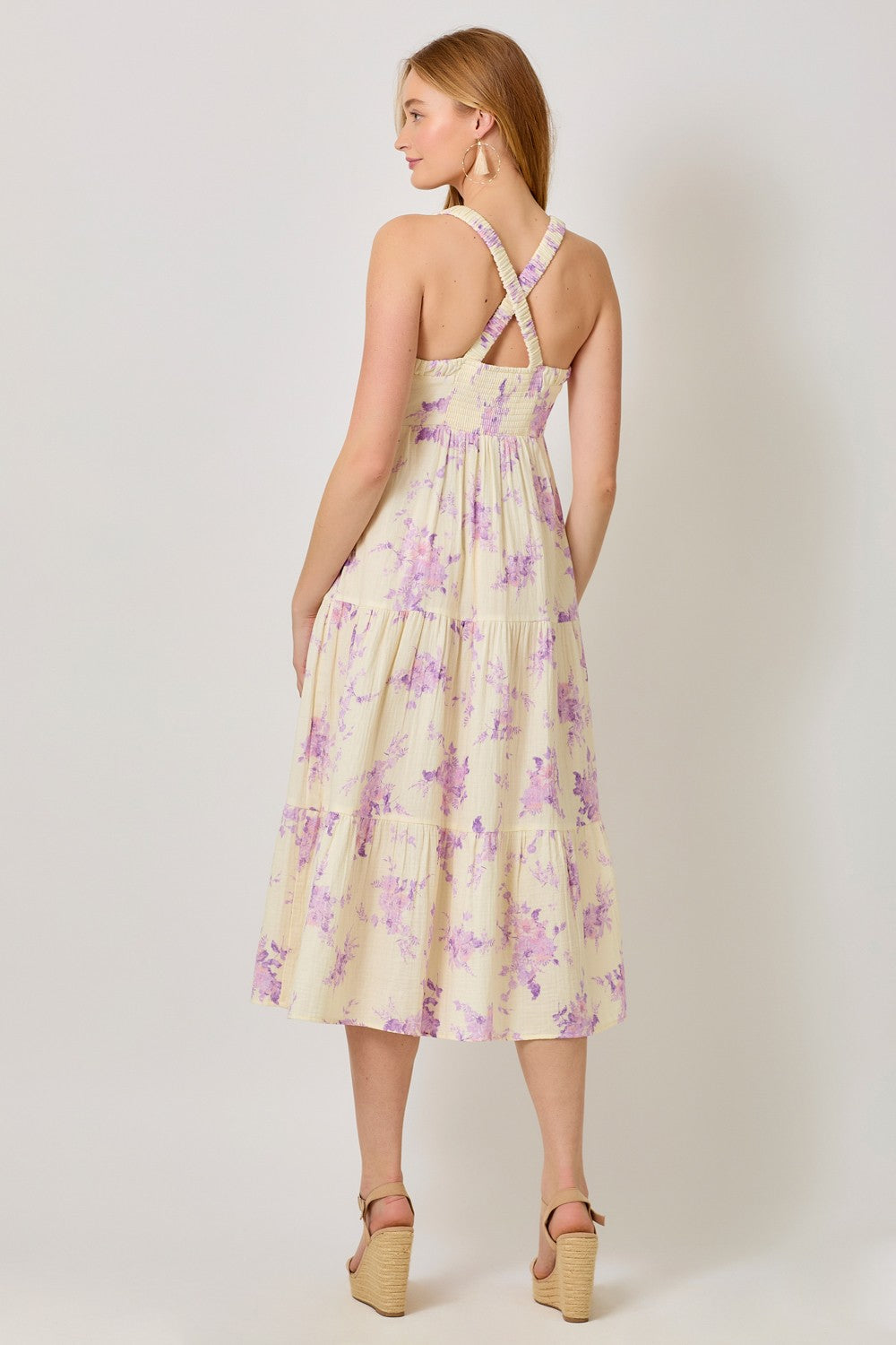 woman wearing a yellow floral midi dress with cross-back straps and tiered skirt, viewed from the back