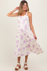 woman wearing a floral print maternity dress with purple flowers and a tiered skirt, showing a baby bump
