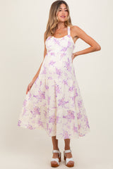 woman wearing a floral purple and cream maternity dress with a tiered skirt and spaghetti straps
