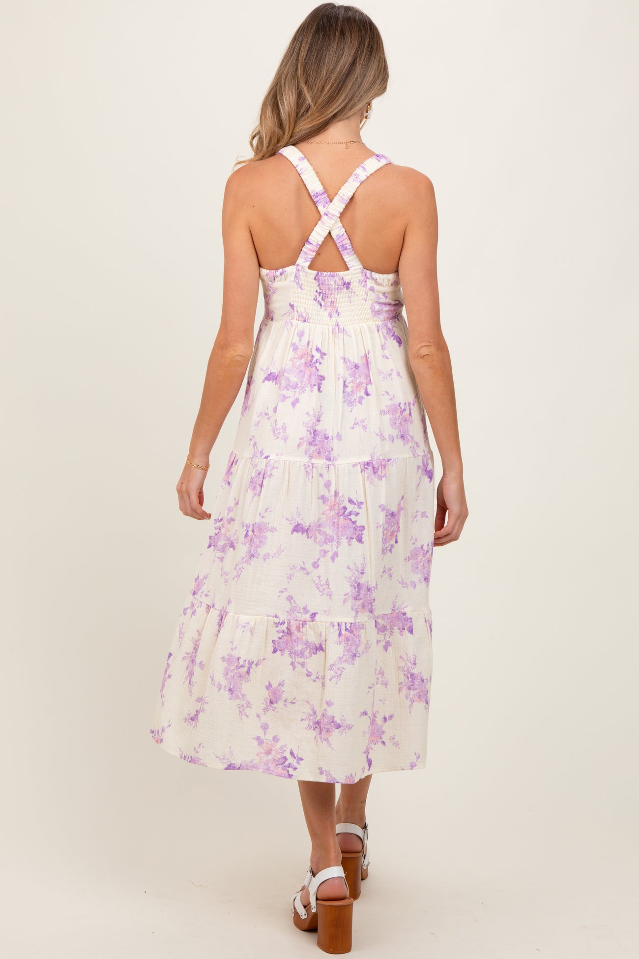woman wearing a floral print maternity maxi dress with a tiered design and crisscross back