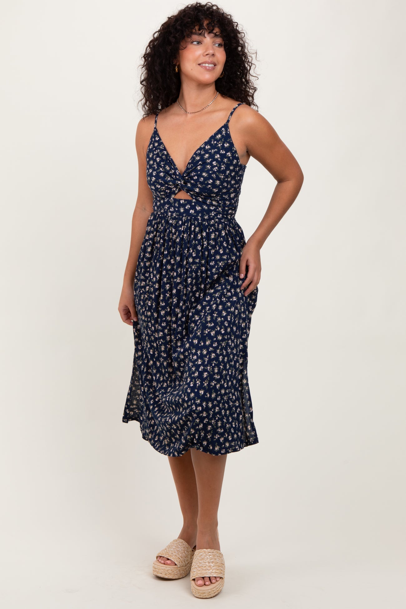 woman wearing a navy blue floral midi dress with a front cutout and adjustable straps