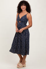 woman wearing a navy floral midi dress with a sweet heart neckline and braided straps, standing and smiling