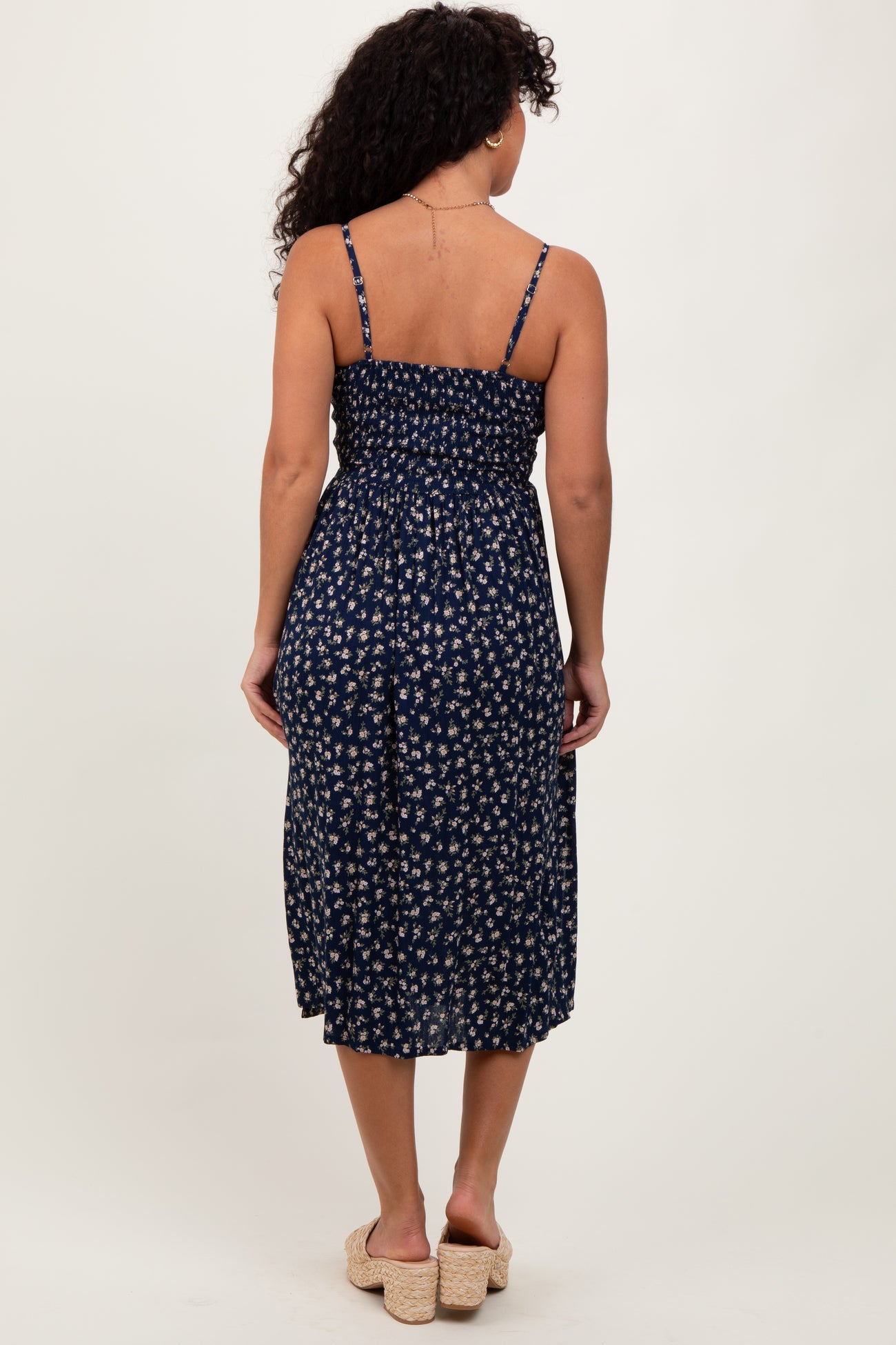 woman wearing a navy blue floral midi dress with adjustable straps and a smocked back