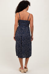 woman wearing a navy blue floral midi dress with adjustable straps and a smocked back