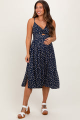 woman wearing a navy blue floral print maternity dress with a knot front and side slit, showcasing her baby bump