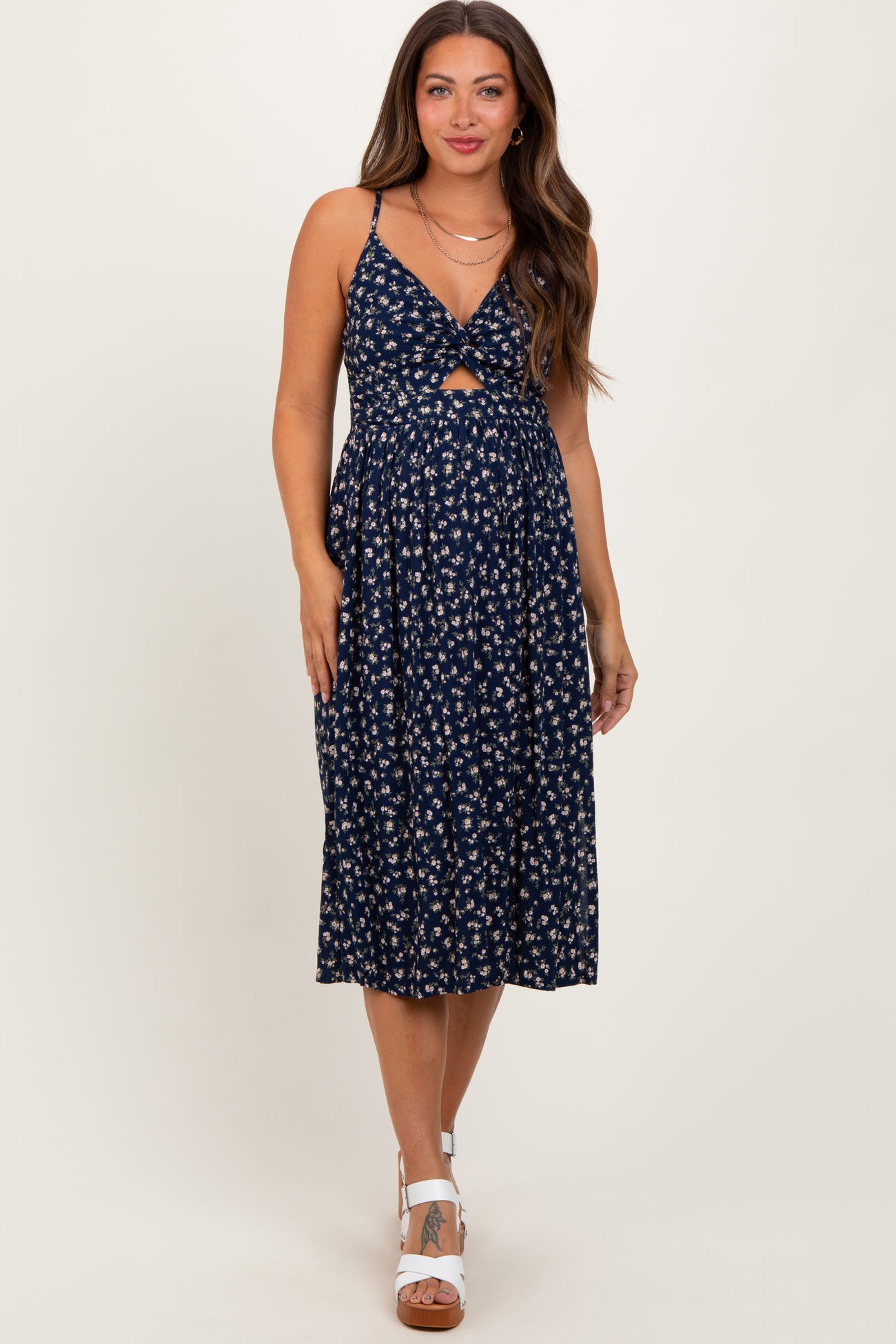 woman wearing a navy floral maternity dress with a front knot detail and a flowy skirt, showcasing her baby bump