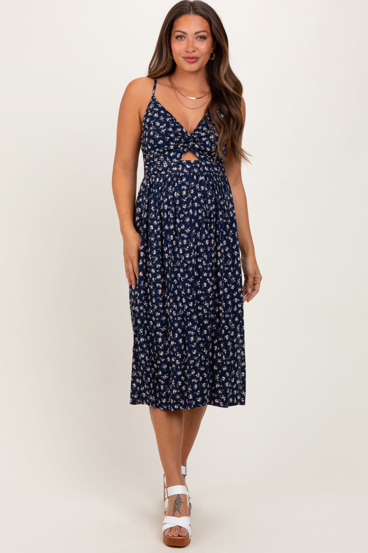 woman wearing a navy floral maternity dress with a front knot detail and a flowy skirt, showcasing her baby bump