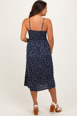woman wearing a navy blue floral maternity dress with adjustable straps and a flowy midi length