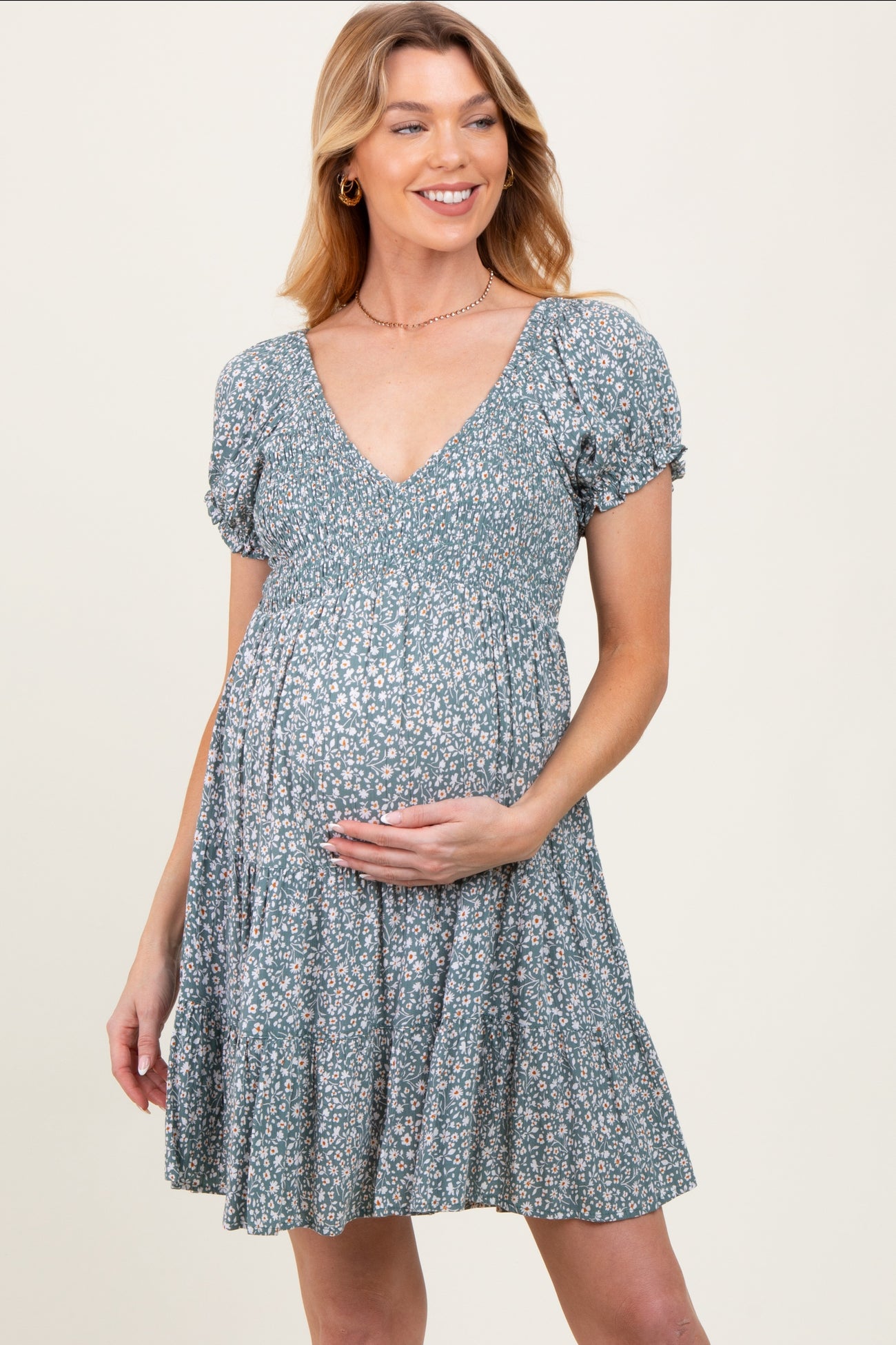 woman wearing a floral maternity dress with a deep v-neck and puff sleeves, holding her baby bump