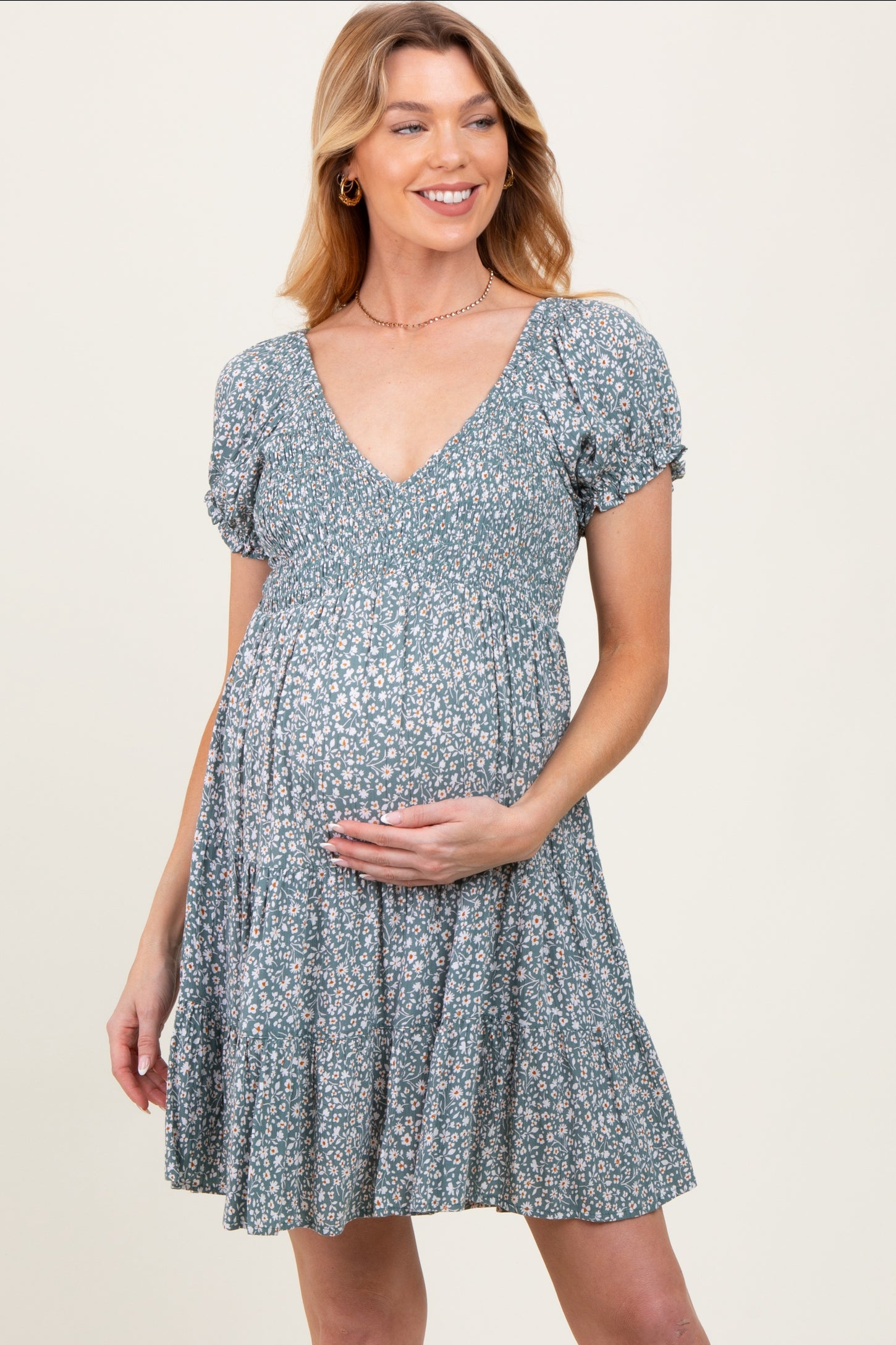 woman wearing a floral maternity dress with a deep v-neck and puff sleeves, holding her baby bump