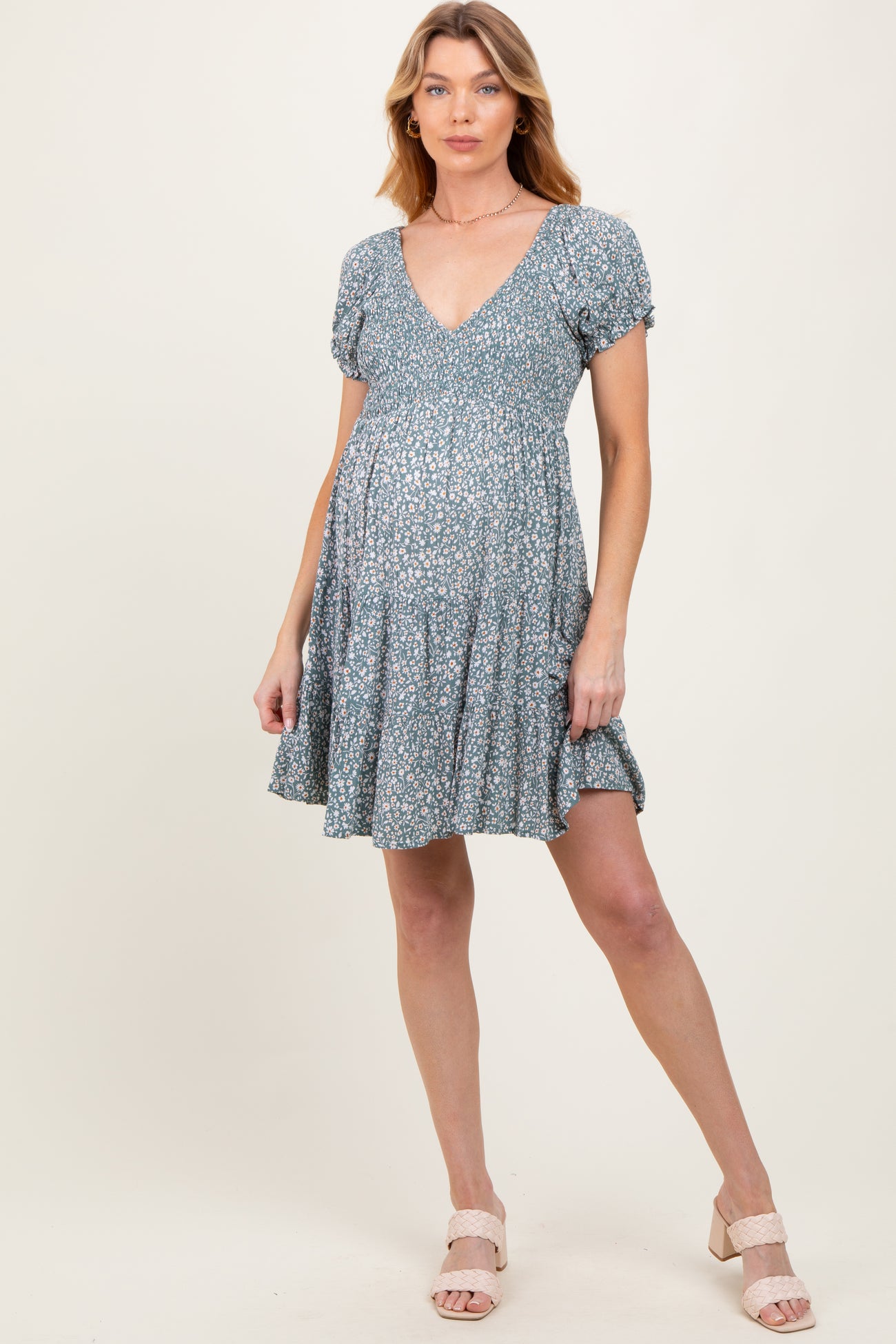 woman wearing a floral print blue maternity dress with a v-neck and short puff sleeves, showing her baby bump