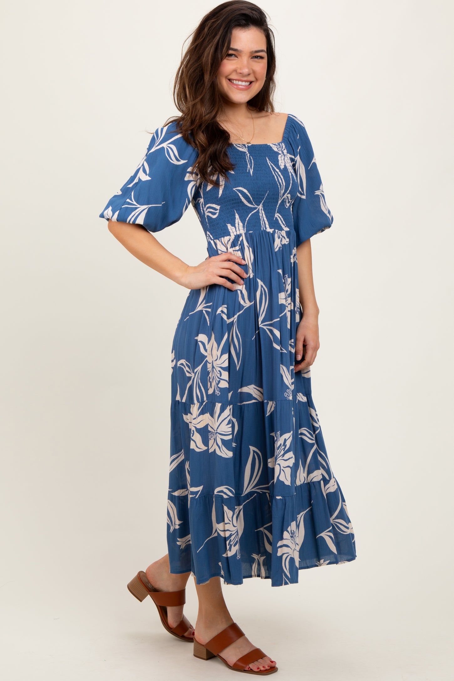 woman wearing a blue floral midi dress with puff sleeves and a smocked bodice, standing with a smile