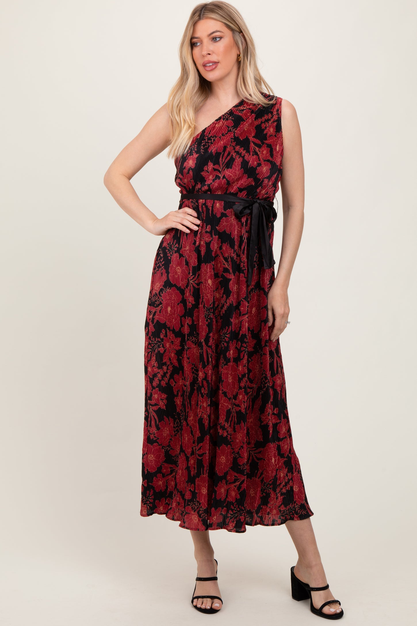woman wearing a black and red floral print one-shoulder maxi dress with a belt and strappy black heels