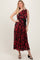 woman wearing a black and red floral print one-shoulder maxi dress with a belt and strappy black heels