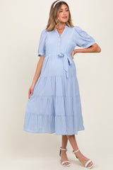 woman wearing a light blue striped maternity midi dress with short puff sleeves and a tie waist detail