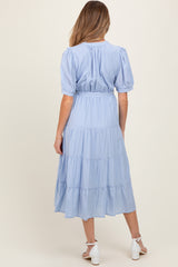 woman wearing a light blue tiered maternity dress with short sleeves and a fitted waist, viewed from the back