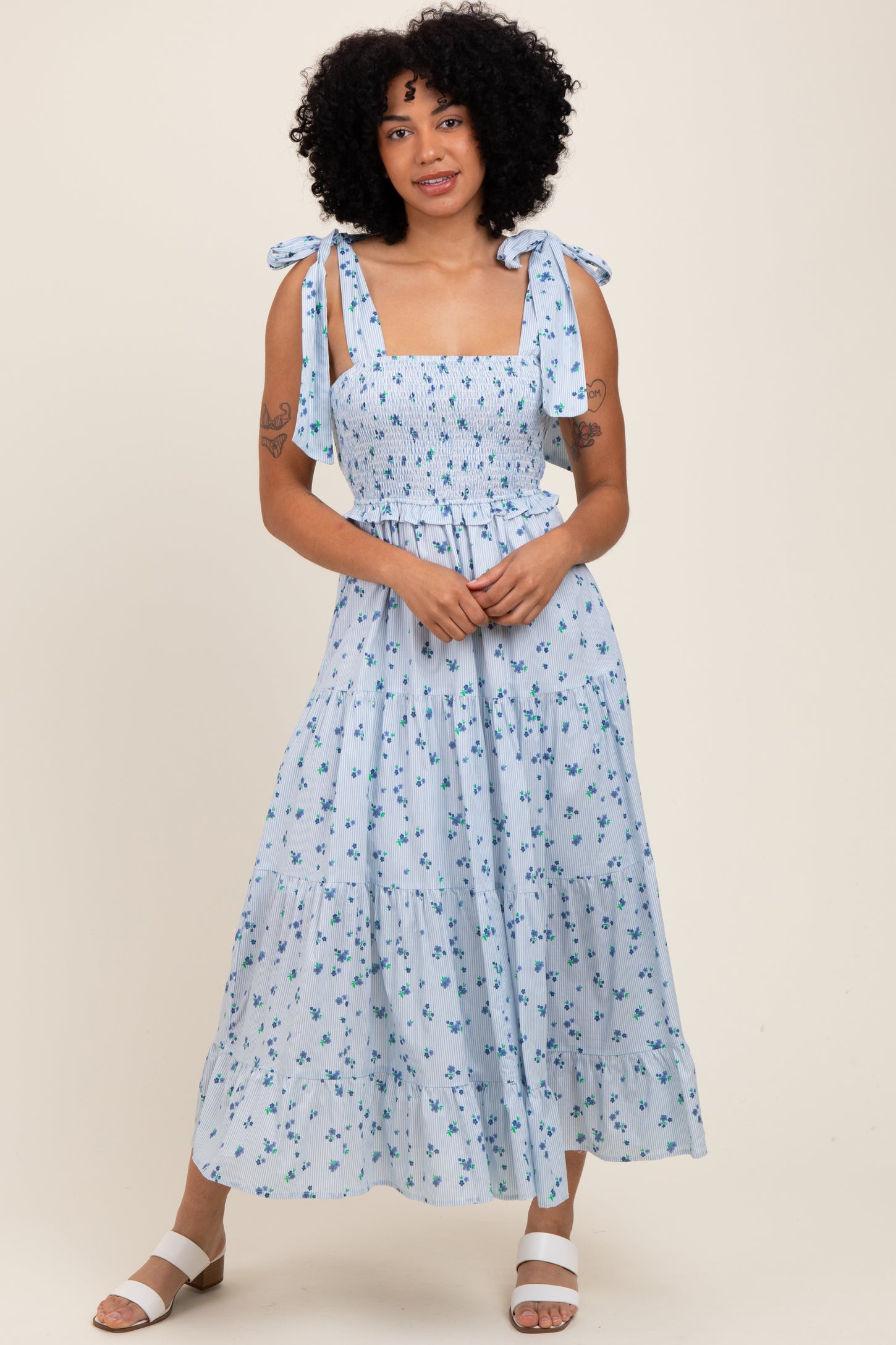 woman wearing a light blue floral maxi dress with smocking and tie shoulder straps