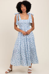 woman wearing a light blue floral maxi dress with smocking and tie shoulder straps