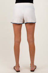 woman wearing white maternity shorts with a scalloped hem and flat sandals, showing the back view