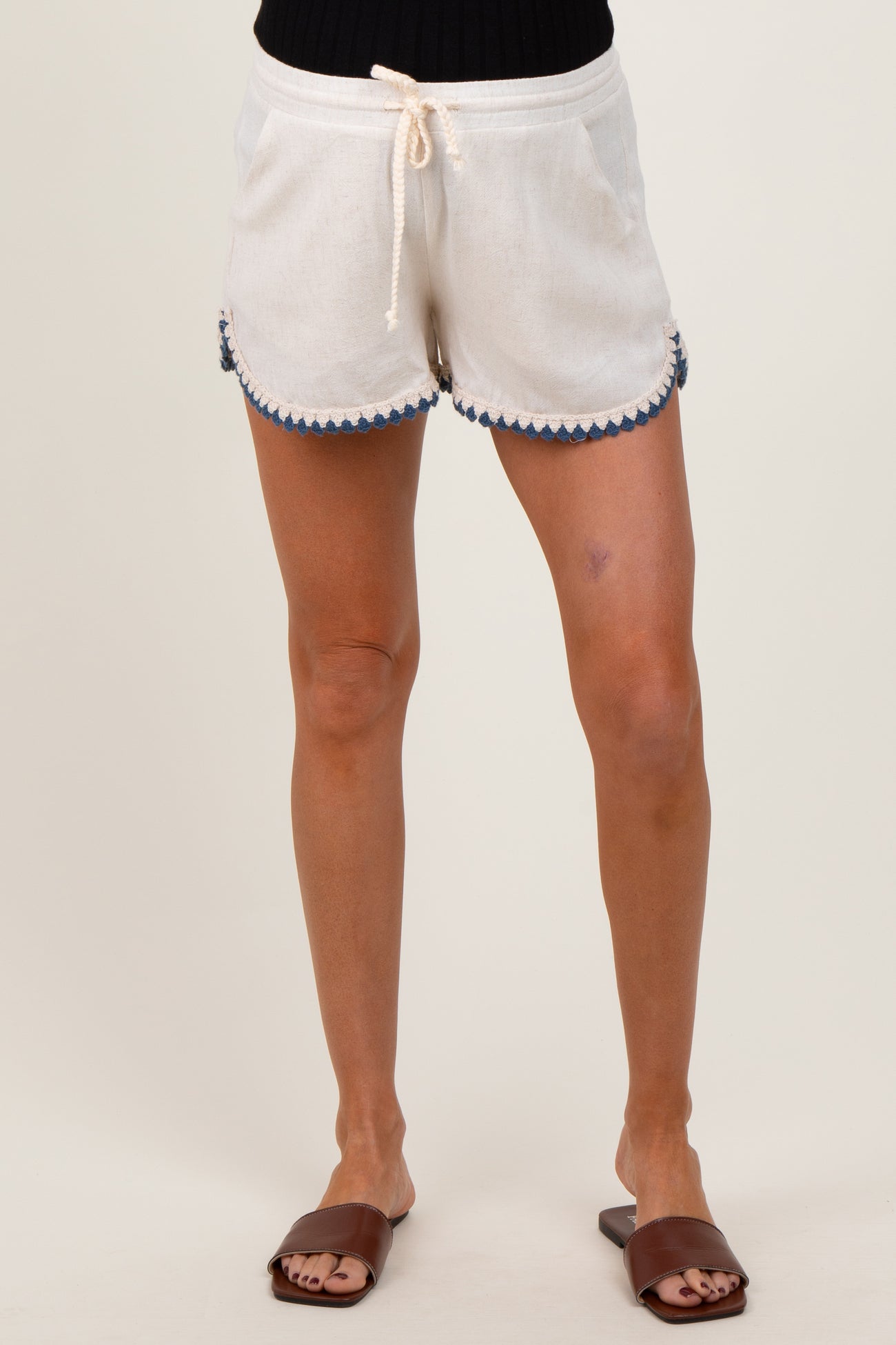 woman wearing white maternity shorts with blue scalloped detailing and drawstring waist