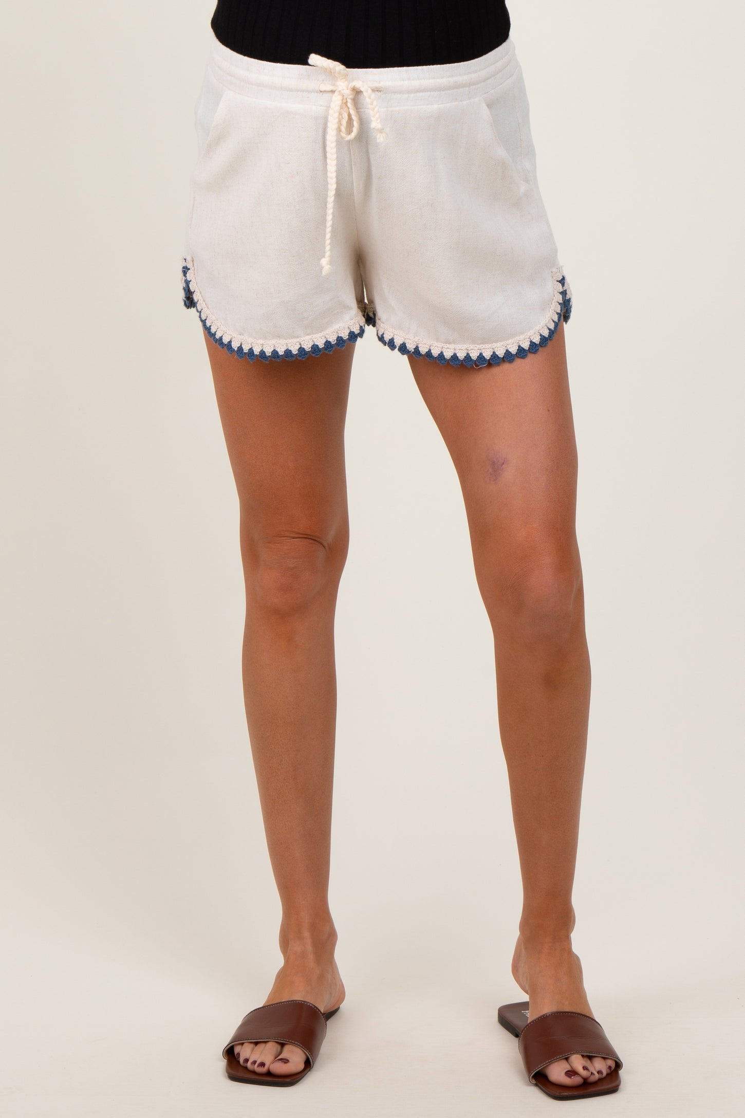 woman wearing white maternity shorts with blue scalloped detailing and drawstring waist